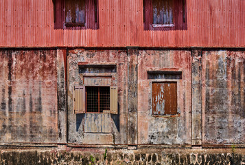 Abandoned pink  building in city. Old stone wall covered with moss. Facade with peeling plasterю. Background  weathered wall with window and door. Natural light.