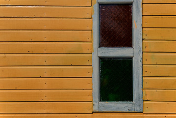 Yellow house with wooden wall  horizontal texture. Old retro wood slats rustic shabby empty background with window. Paint peeled yellow weathered  surface. Natural wood board panel grunge facade..