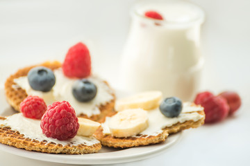 Waffles with cheese, yogurt and raspberries. A delicious wholesome breakfast on a light background. Very soft selective focus.
