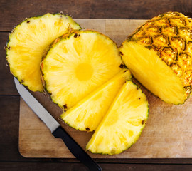 Pineapple on wood texture background. Whole and sliced tropical pineapple on wooden cutting board ...