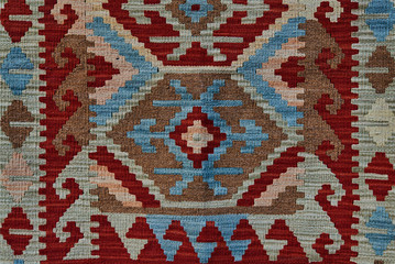 Close up of geometric patterned carpet. Hand woven rug with red, yellow, blue and other colors. Hand woven carpet with abstract design. Colorful carpet. Textile background. Abstract background.