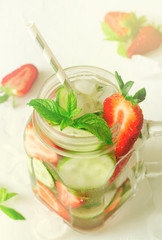 Summer refreshing iced drinks with orange, lemon, cucumber and strawberry on white background