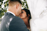 Bride and groom in a park kissing.couple newlyweds bride and groom at a wedding in nature green forest are kissing photo portrait.Wedding Couple