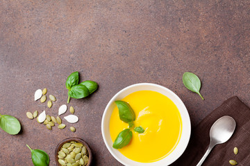 Autumn vegetable or pumpkin soup in white bowl on stone kitchen table top view. Empty space for recipe.