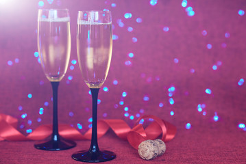 Champagne glasses on sparkling holiday background. Fireworks at New Year party and holiday celebration concept. Photo of two champagner glasses against background with sparkles.