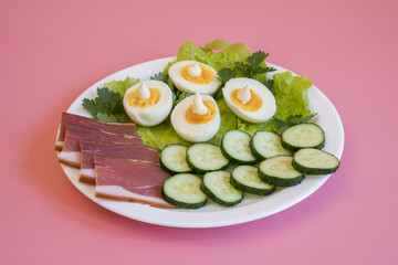 breakfast. Boiled eggs, bacon, greens in a white plate on pink background. White plate with food on a pink background