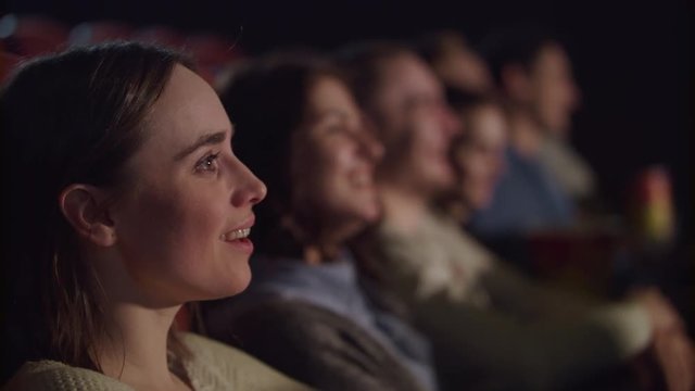 Smiling girl watching theater performance and laughing. Spectators have fun. Cinema people watching comedy movie. Close up of woman face watching funny movie at cinema in slow motion