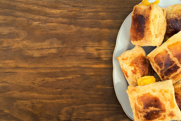 Baked in the oven cheese rolls of puff pastry with a Golden crust in the plate, top view on a wooden background.