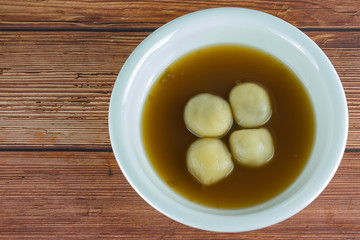  Black Sesame Dumplings in Ginger Tea or Bualoy, thai dessert street food  in white bowl on wooden table background