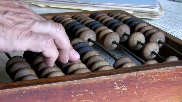 Close up of hand of man counting finance using old style calculator, wooden abacus