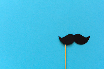 Paper mustache on booth props on blue paper background. Cut out style. Movember concept. Top view....