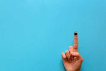 Fingers with a mustache and cylinder on blue paper background. Movember concept. Top view. Flat lay.