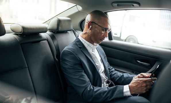 Businessman sitting in car using mobile phone