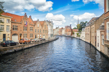 Fototapeta na wymiar Bruges canal, buildings, church and a metal wire installation on a sunny day
