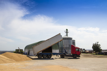 truck unloading grain near a silo