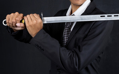 Businessman Holding Sword Over Black Background