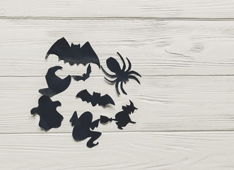 halloween flat lay. happy halloween concept, space for text. witch ghost bats and spider black decorations on white wooden background top view. simple cutouts for  holiday celebration. 