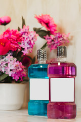 Bottles of mouthwash with colorful artificial flower in the background