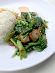 Stir fry Kai Land and crispy pork, stir fried rice with rice in white dish on white background. Thai style food.