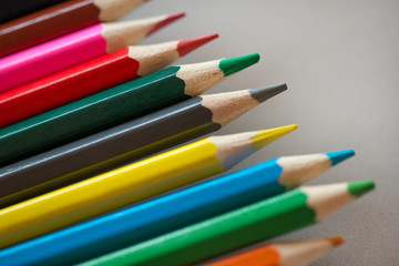 Pile of sharp coloured drawing pencils on table. Rainbow colors  red, yellow, blue, green, purple. Concept of art, crafts and kids having fun