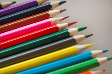 Pile of sharp coloured drawing pencils on table. Rainbow colors  red, yellow, blue, green, purple. Concept of art, crafts and kids having fun