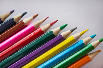 Fototapeta premium Pile of sharp coloured drawing pencils on table. Rainbow colors red, yellow, blue, green, purple. Concept of art, crafts and kids having fun