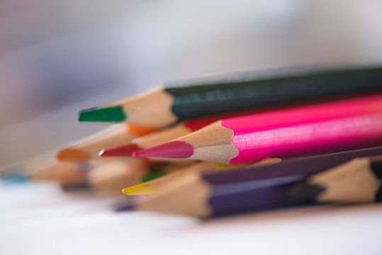 Pile of sharp coloured drawing pencils on table. Rainbow colors  red, yellow, blue, green, purple. Concept of art, crafts and kids having fun
