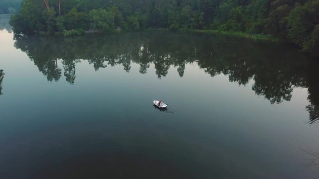 aerial view of young readhead female traveler in the boat on the lake with two siberian husky dogs