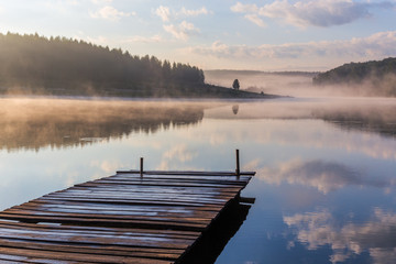 sunrise over the foggy river with a wooden pier