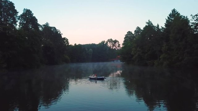 aerial view of young readhead female traveler in the boat on the lake with two siberian husky dogs