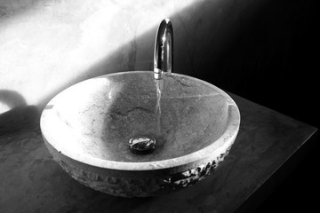 Black and white round stone-like basin in the modern bathroom - obrazy, fototapety, plakaty