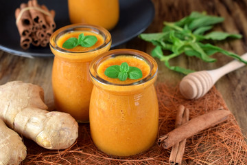 Yellow smoothie with berries of sea buckthorn in glass jars topped with mint
