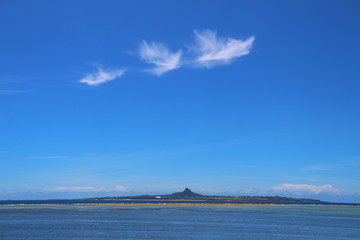 Clear blue sky with bird-like clouds and skyline of the mountain