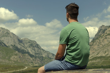 sitting guy on the background of the mountains