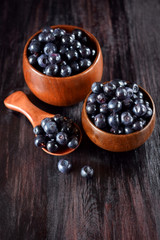 Bilberries in wooden bowls against the dark wooden background