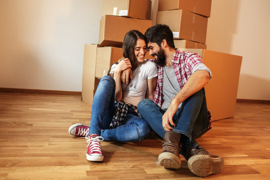 Young couple moving into a new home.Sitting on floor in empty apartment .Real estate concept.