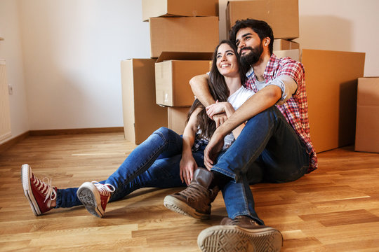 Young couple moving into a new home.Sitting on floor in empty apartment .Real estate concept.