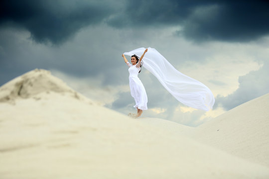 Piękna dziewczyna w białej sukni ślubnej z długim welonem na piaszczystej wydmie. © Stanisław Błachowicz