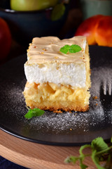 Piece of meringue pie with fruits and cottage cheese on a dark plate