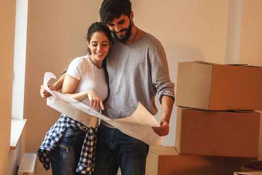 Young couple moving into a new house.They unpacking and finding ideas for interior design.