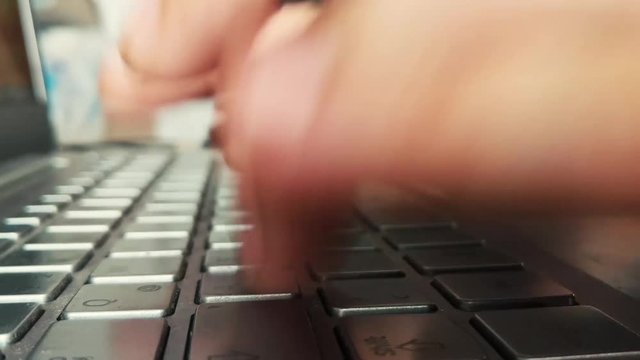 Hands typing fast on laptop keyboard.