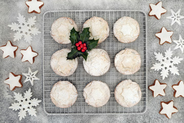 Fototapeta na wymiar Christmas mince pies on a baking rack with gingerbread cookies, holly and berry leaf sprig, snowflake decorations and icing sugar dusting, holiday fresh baked food concept. Flat lay.