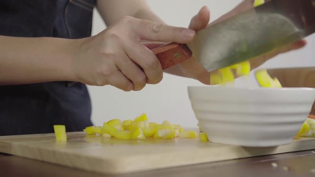 Close up of chief woman making salad healthy food and chopping bell pepper on cutting board.