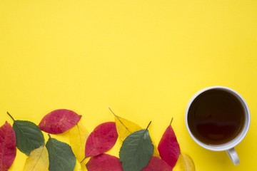 Fototapeta na wymiar Abstraction, the concept of autumn. Autumn leaves and a Cup of coffee on a yellow background.