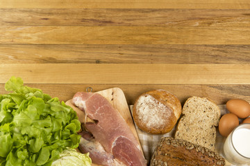 Set products consisting of bread, milk, pork, eggs , and vegetable on wooden table background, fresh food for cooking