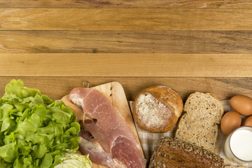 Set products consisting of bread, milk, pork, eggs , and vegetable on wooden table background, fresh food for cooking