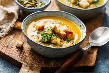Pumpkin and carrot soup with cream and parsley.
