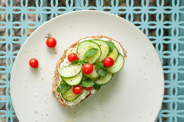A Mediterranean twist on bruschetta with cream cheese, mint, cucumber and mini tomatoes on a graphic background.