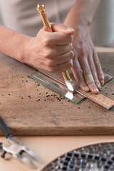 Artist cutting sheets of stained glass into small mosaic squares. Close-up