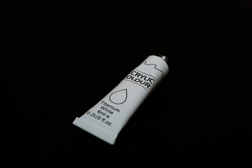 Acrylic white titanium paint metal tube on black background. New tube. Aluminium tube of paint.